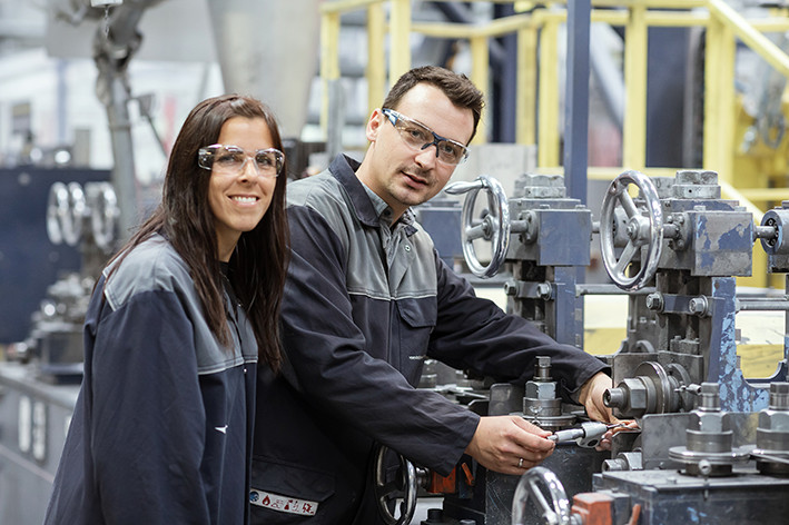 A female and a male employee of voestalpine working on a machine.