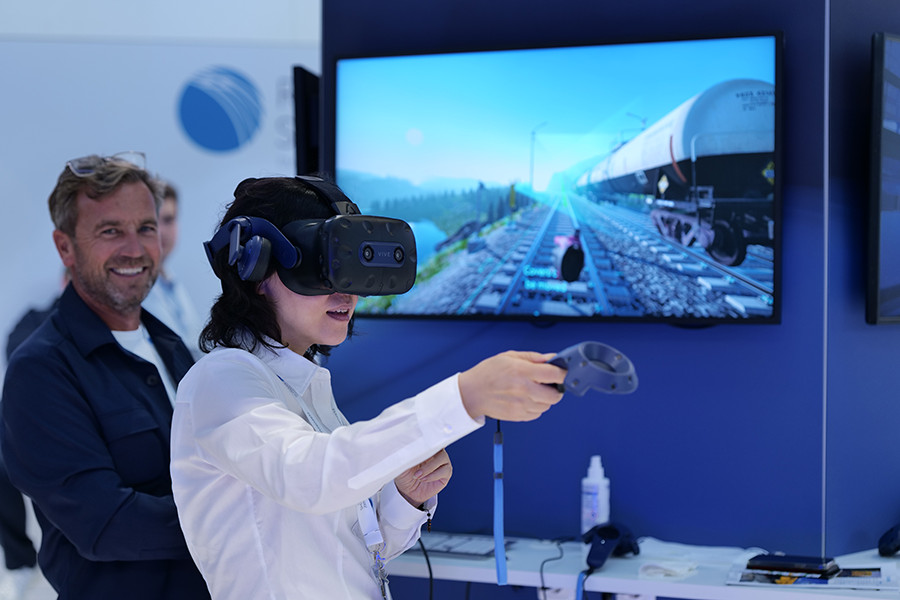 Eine Person mit VR Brille und Controller testet den aktuellen Stand der Technik am voestalpine Messestand.