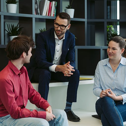 Justin sits together with 2 other voestalpine employees in a modern environment and talks.