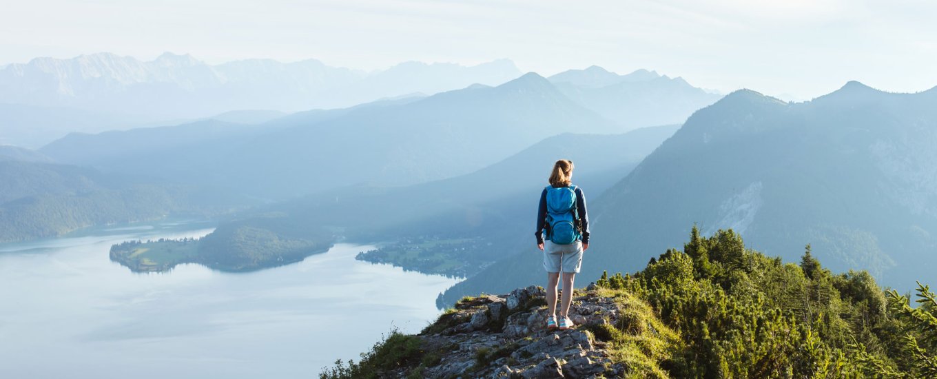 Hiker standing on mountain looking over lake