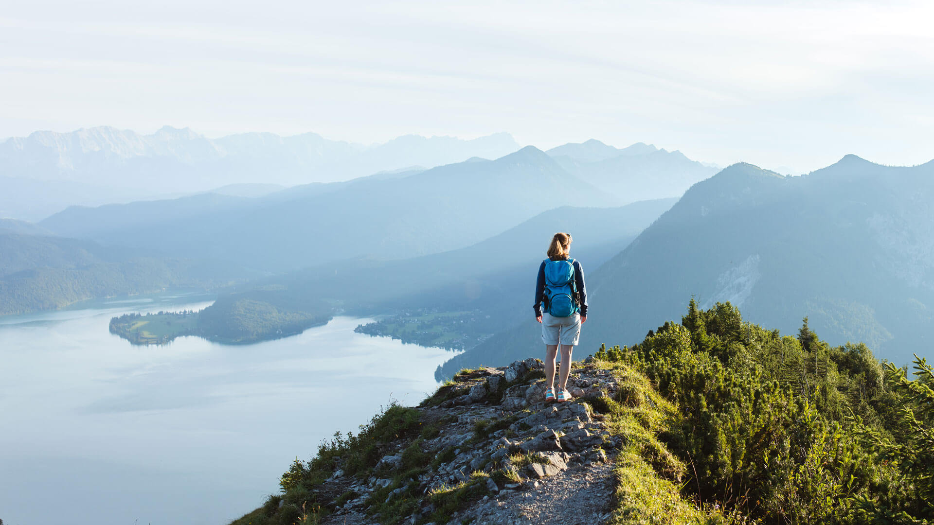 Hiker standing on mountain looking over lake