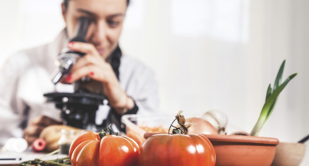 Female nutritionist analyzing food using a microscope