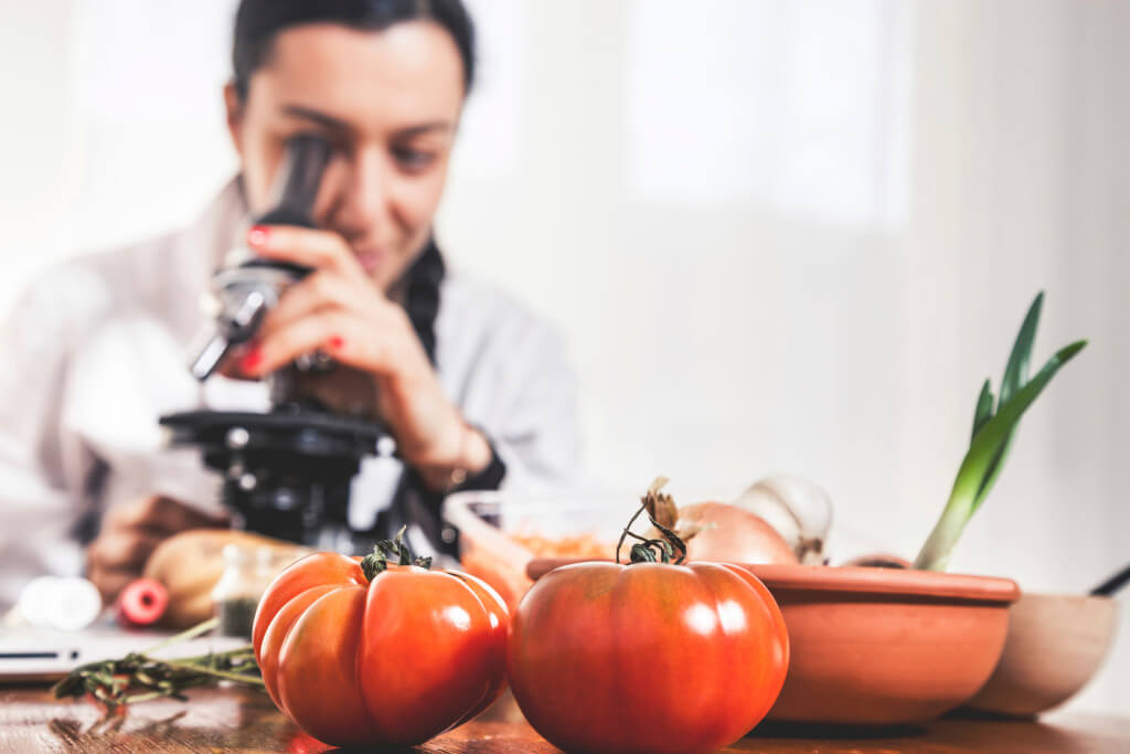 Female nutritionist analyzing food using a microscope