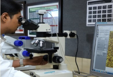 A person looking through microscope in a voestalpine Metallurgical lab