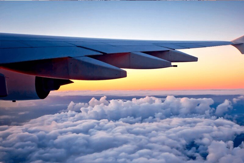 View of a sunset above the colouds and a plane wing taken from inside an airplane