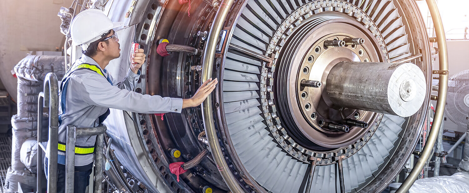 man in safety gear inspecting a gas turbine in production